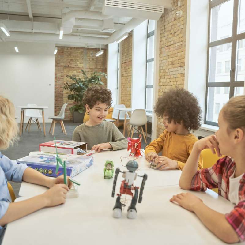 Collaboration. Clever diverse kids sitting at the table, examining technical toys full of details